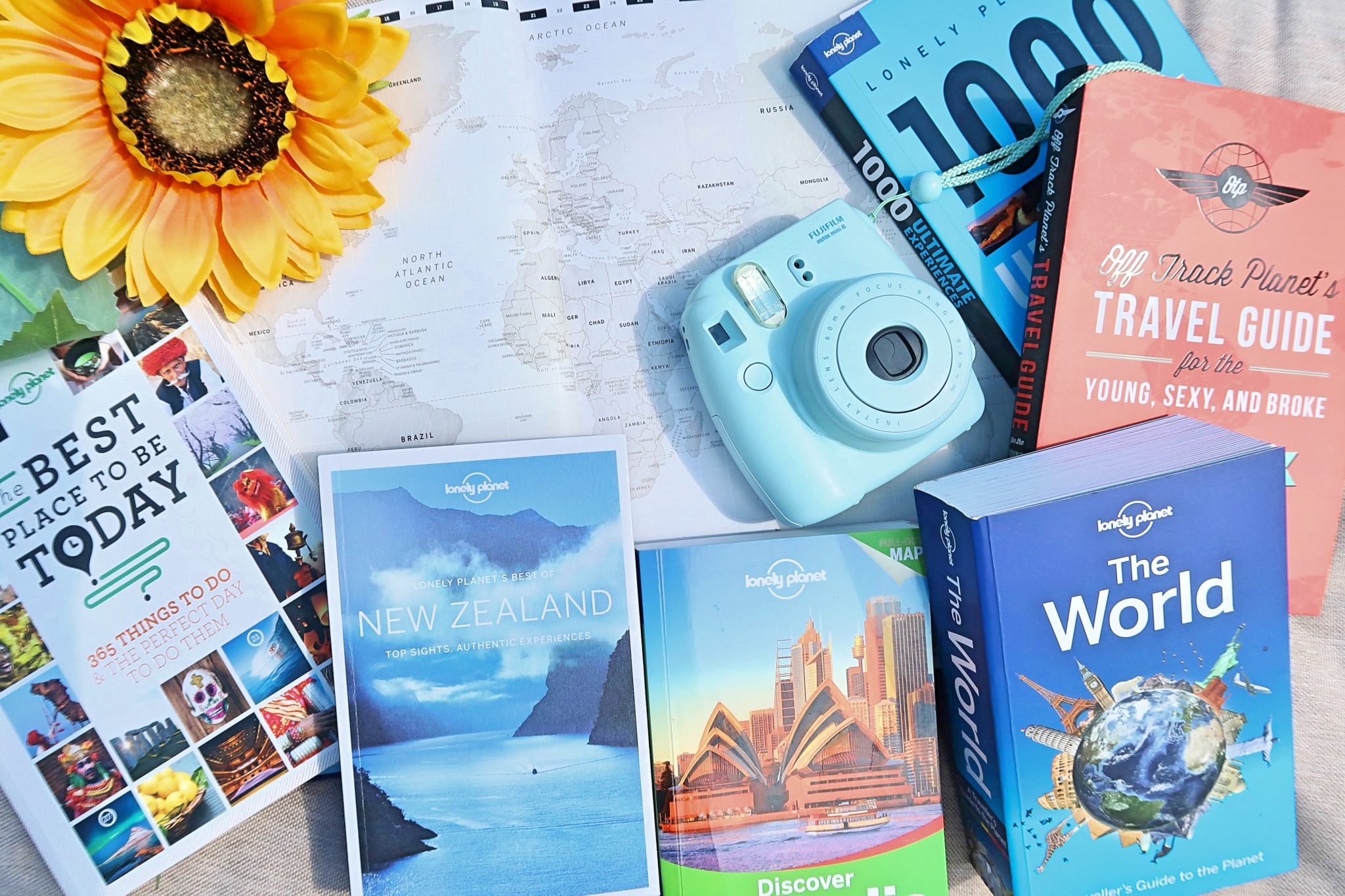 Ultimate Travel Bucket List - flat lay photo including travel guides, instax camera and map background. 